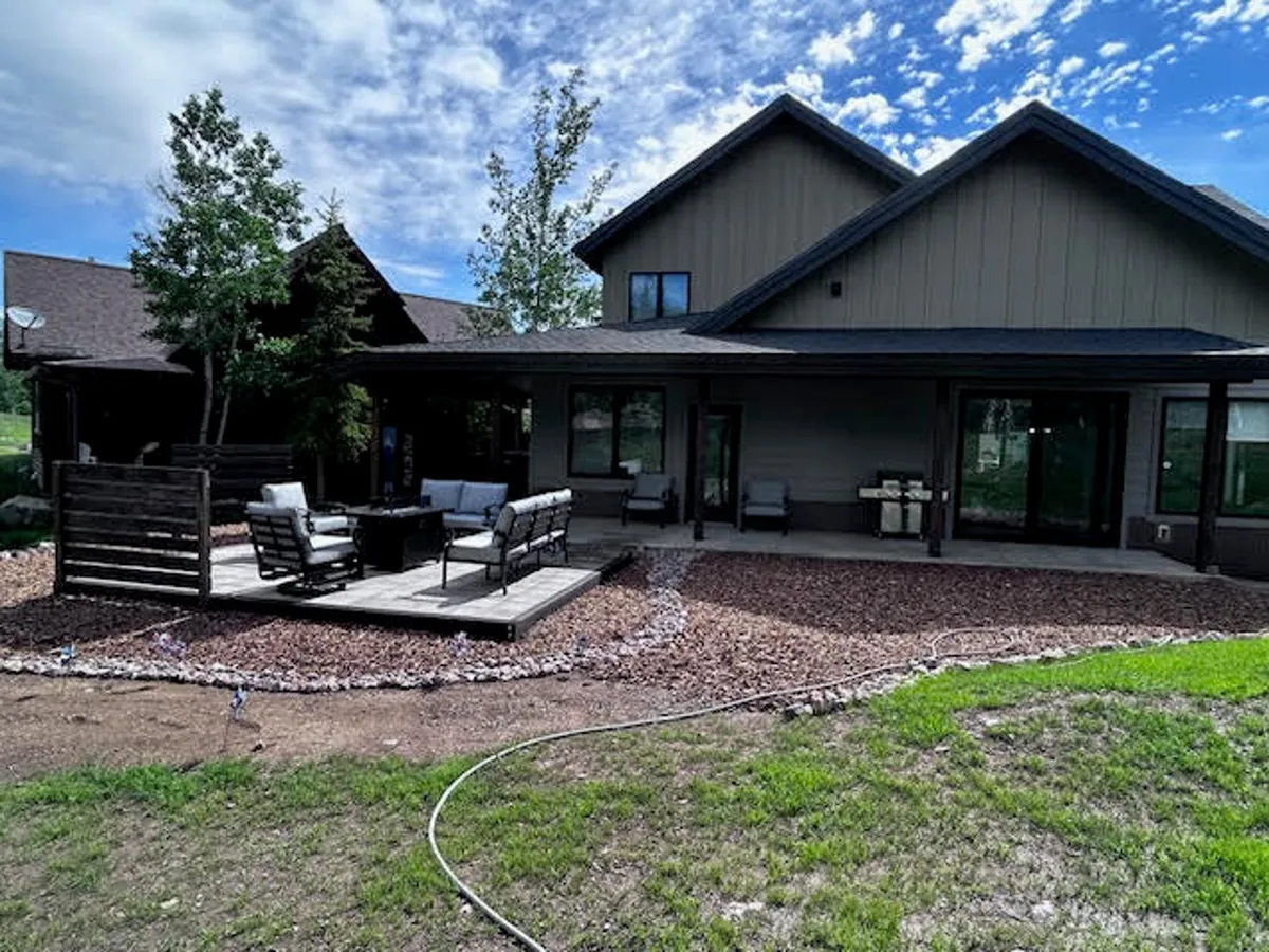 A spacious back deck is furnished with comfortable patio seating and overlooks landscaped gardens. The deck area is bathed in natural light, perfect for outdoor dining, relaxing, or enjoying sunsets and morning coffee.