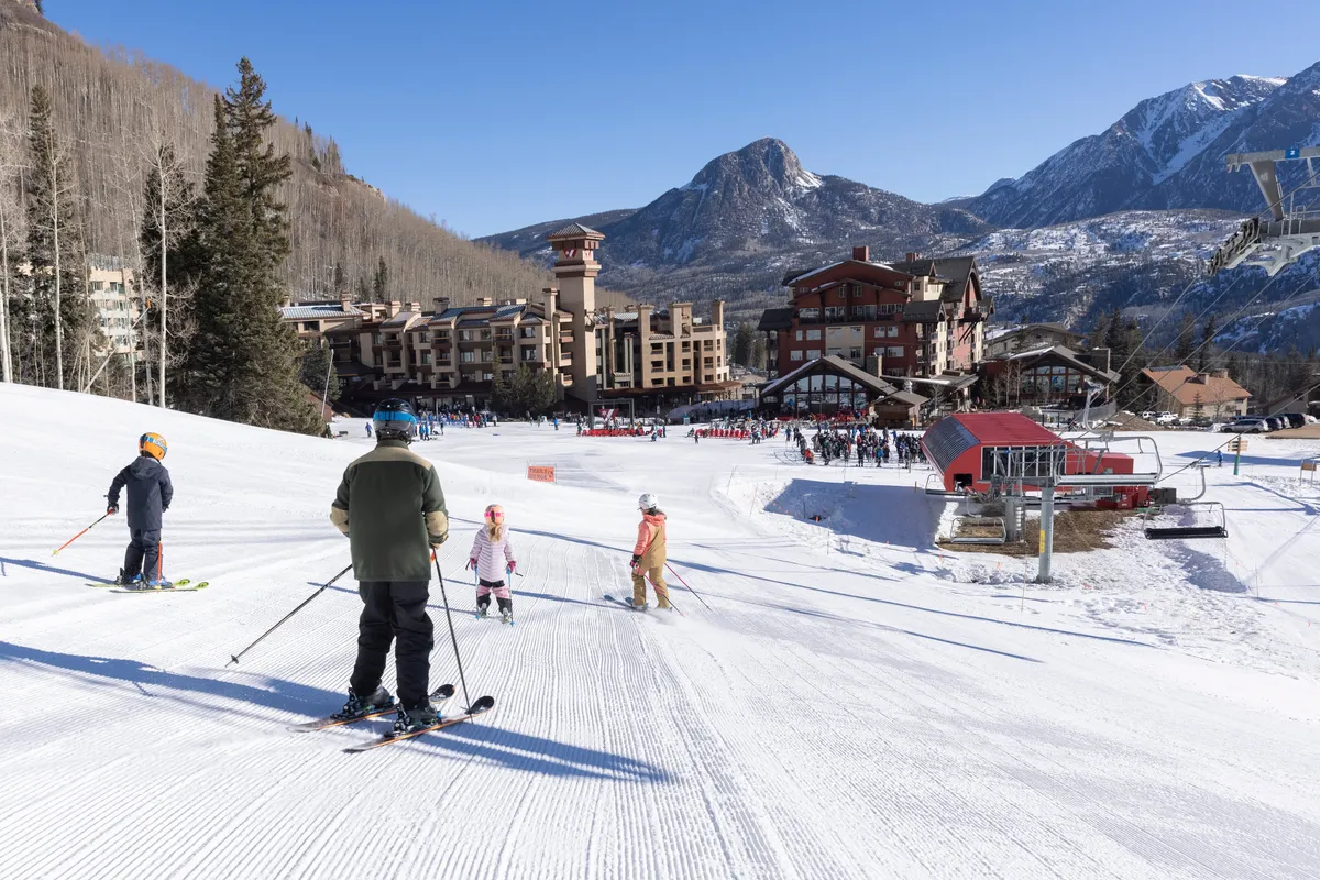 A lively exterior scene featuring skiers on the slopes, the ski resort with visible ski lifts, and the stunning backdrop of the Colorado mountains. Snow blankets the ground, and families can be seen enjoying winter sports together, capturing the energy and excitement of the ski resort experience.
