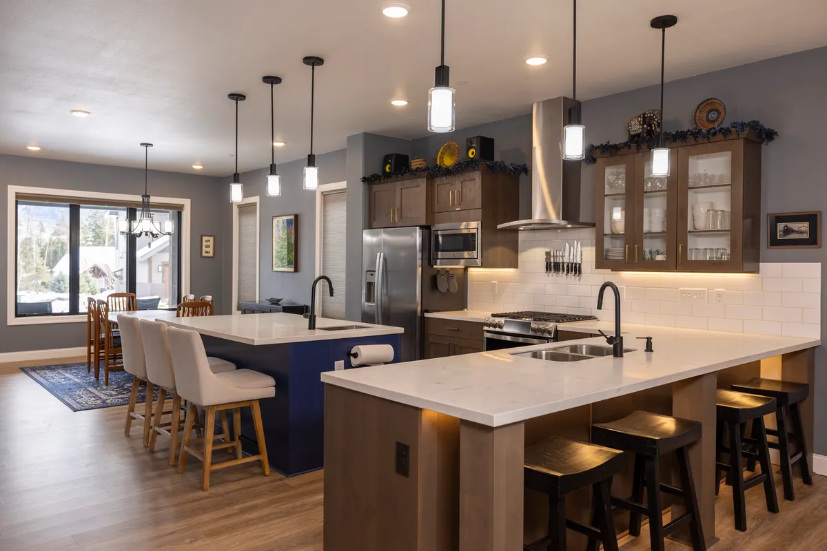 A bright open-concept kitchen and dining area featuring an island with bar stools, modern appliances, a spacious dining table, and large windows that flood the space with natural light. The layout is seamless, inviting, and ideal for both cooking and gathering.